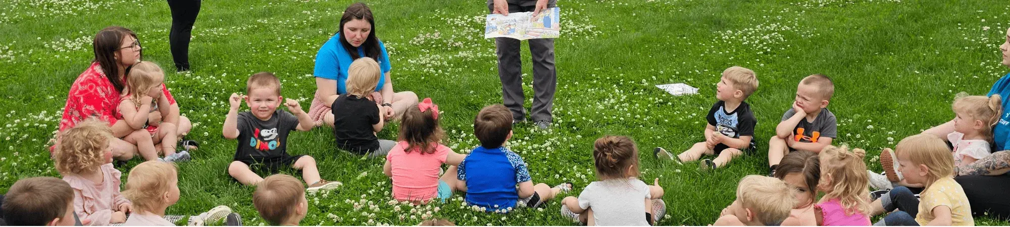 Children sitting in the grass listening to a story